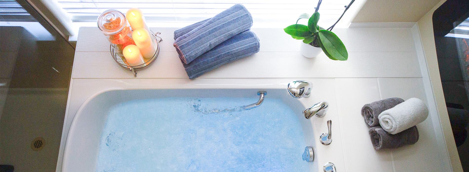 The image displays a bathroom scene with a bathtub, towels on a rack, a potted plant, and various other items typically found in a bathroom setting.