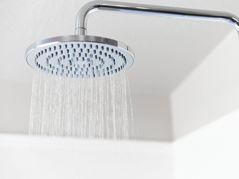 A modern silver showerhead with multiple nozzles attached to a wall-mounted shower fixture.