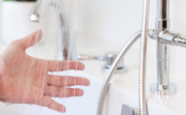 The image shows a person washing their hands at a sink with chrome fixtures.