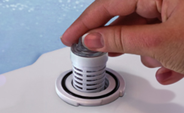 A person s hand manipulating a small, circular object with two black rings on top, set against a white background.